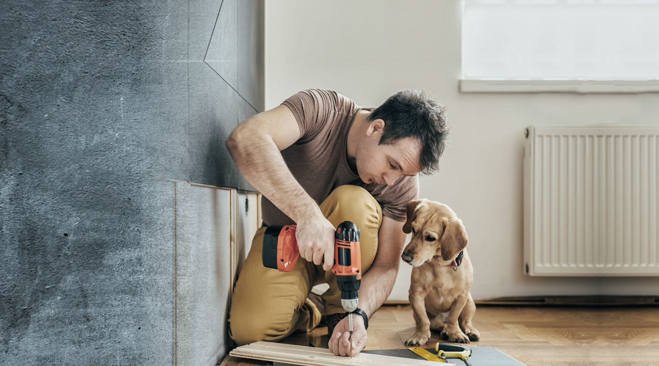 man with drill working on home next to dog